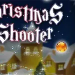 Text stilizat Christmas Shooter pe un fundal de iarnă cu case acoperite de zăpadă și globuri colorate
