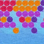 Bile colorate în nuanțe de roșu, portocaliu, violet și lila dispuse pe un fundal albastru