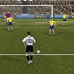 Un jucător de fotbal în tricou alb-negru se pregătește să execute un penalty, în fața unui portar și a patru apărători în tricouri galbene, pe un teren cu porți și public în fundal