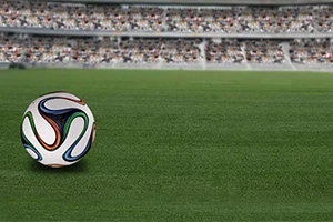 Minge de fotbal pe un teren cu iarbă, având în fundal tribunele unui stadion