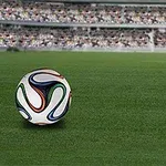 Minge de fotbal pe un teren cu iarbă, având în fundal tribunele unui stadion